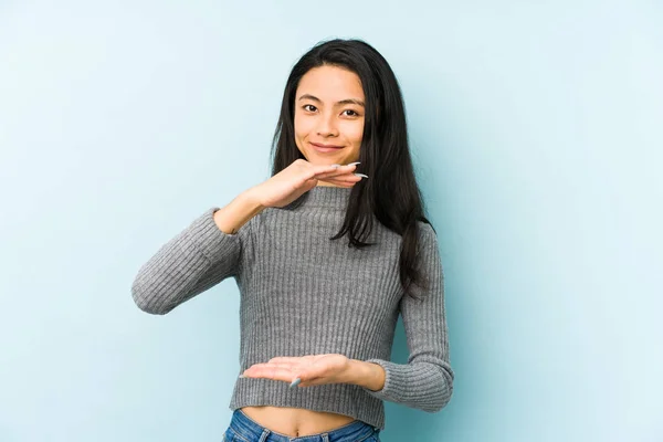 Mladá Číňanka Izolované Modrém Pozadí Drží Něco Oběma Rukama Prezentace — Stock fotografie