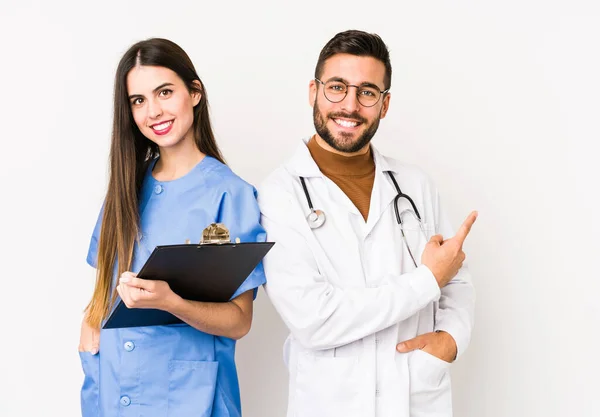 Joven Doctor Una Enfermera Aislados Sonriendo Señalando Lado Mostrando Algo —  Fotos de Stock