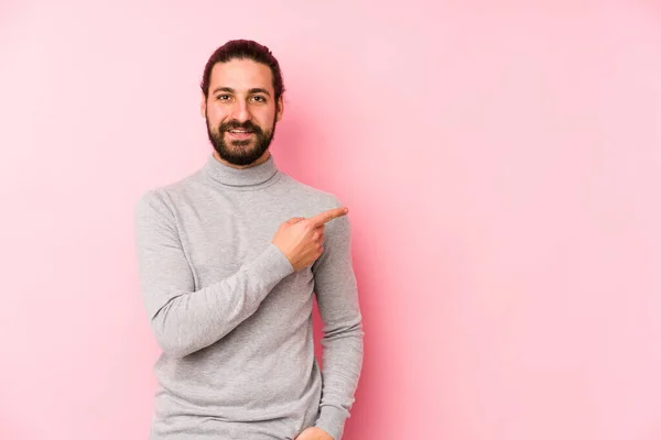 Joven Hombre Pelo Largo Aislado Sobre Fondo Rosa Sonriendo Señalando — Foto de Stock