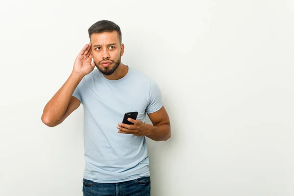 Jovem Mestiço Asiático Homem Segurando Telefone Tentando Ouvir Uma Fofoca — Fotografia de Stock