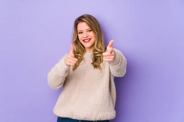 紫の背景に孤立した若い白人女性明るい笑顔を前に指して — ストック写真