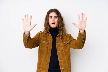 Uzun saçlı adam yalnız poz veriyor. 10 numarayı elleriyle gösteriyor..