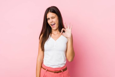 Genç, tatlı bir kadın göz kırpıyor ve elleriyle iyi bir jest yapıyor..