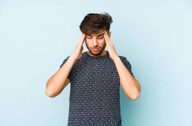 Mavi arka planda izole edilmiş genç bir Arap tapınaklara dokunuyor ve başı ağrıyor..