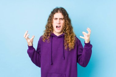 Uzun saçlı adam öfkeyle bağırıyor..