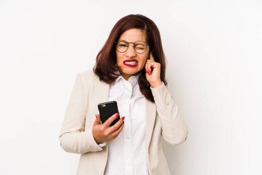 Orta yaşlı Latin bir kadın cep telefonu tutuyor kulaklarını elleriyle kapatıyor..