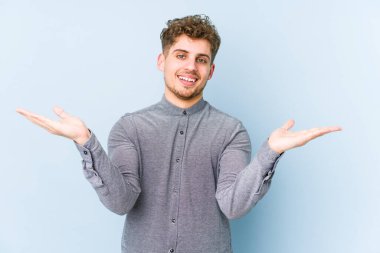 Sarışın, kıvırcık saçlı, beyaz tenli, soyutlanmış bir adam kollarıyla ölçeği yapıyor, mutlu ve kendinden emin hissediyor..