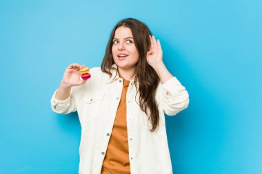 Kurabiye tutan genç kadın dedikoduları dinlemeye çalışıyor..