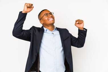 Genç iş adamı beyaz arka planda izole edilmiş özel bir günü kutluyor, atlıyor ve enerjiyle kollarını kaldırıyor..