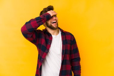 Sarı arka planda izole edilmiş genç beyaz adam ellerini başının üstünde tutarak neşe içinde gülüyor. Mutluluk kavramı.