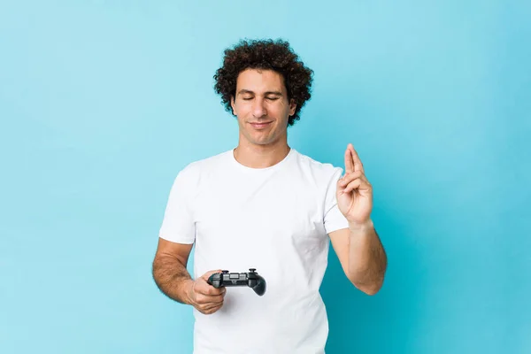 Jovem Caucasiano Encaracolado Homem Segurando Controlador Jogo Cruzando Dedos Para — Fotografia de Stock