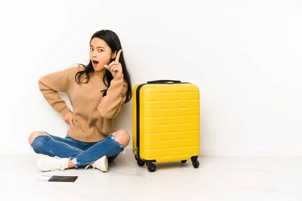 若い中国人旅行者の女性が座っています床にスーツケースで隔離されたアイデア インスピレーションの概念を持っている — ストック写真