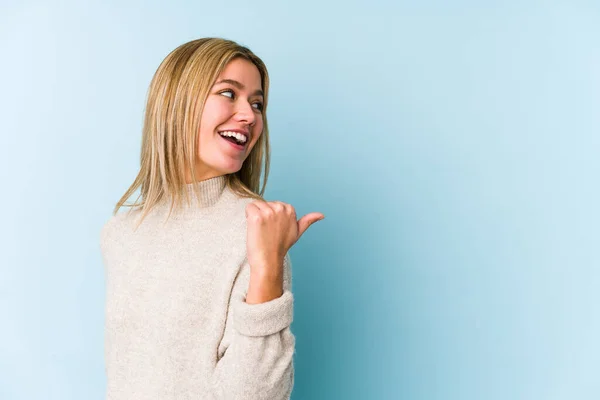Young Blonde Caucasian Woman Isolated Points Thumb Finger Away Laughing — Stock Photo, Image