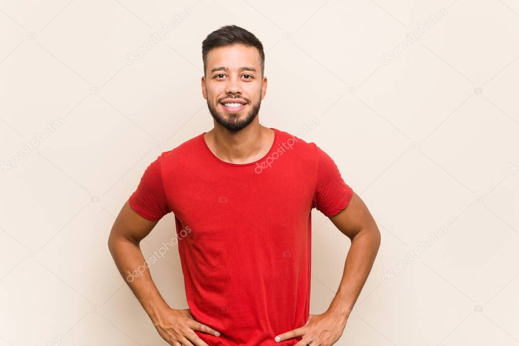 Young south-asian man confident keeping hands on hips.