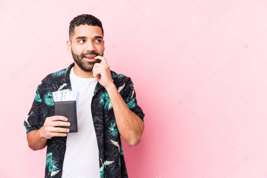 Young arabian cool man holding a boarding passes isolated relaxed thinking about something looking at a copy space.