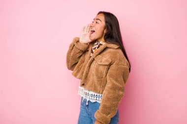 Koyun derisi paltosu giymiş genç bir Hintli kadın bağırıyor ve avuç içini açık tutuyor..