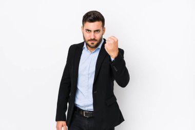 Beyaz arka planda beyaz tenli genç beyaz bir iş adamı kameraya yumruk gösteriyor, agresif bir yüz ifadesi..