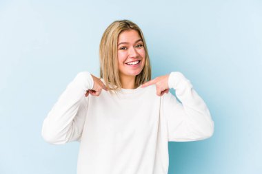 Sarışın, beyaz tenli, izole bir kadın. Parmakla işaret ederek şaşırmış, gülümseyerek..