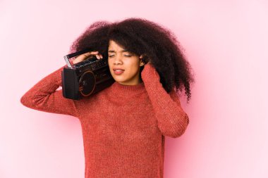 Elinde kaset tutan genç bir afro kadın. Elleriyle kulaklarını kapatıyor..