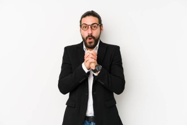 Kafkasyalı genç iş adamı beyaz bir arka planda izole edilmiş şans için dua ediyor, şaşırıyor ve ağzını açıyor..