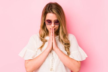 Pembe arka planda gözlüklü genç beyaz kadın. Dua ediyor, bağlılık gösteriyor. İlahi ilham arayan dindar kişi..