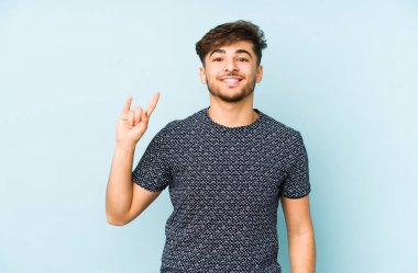 Genç Arap adam mavi arka planda izole edilmiş boynuzları devrim konsepti olarak gösteriyor..