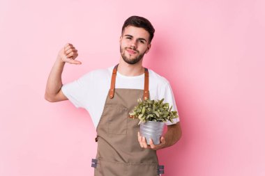 Kafkas 'lı genç bahçıvan bir bitkiyi tek başına tutuyor gururlu ve kendinden emin hissediyor, örnek olarak..
