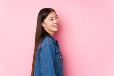 Pembe arka planda poz veren genç Çinli bir kadın..