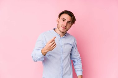 Pembe arka planda poz veren beyaz bir genç seni işaret ederek sanki seni davet ediyormuş gibi..