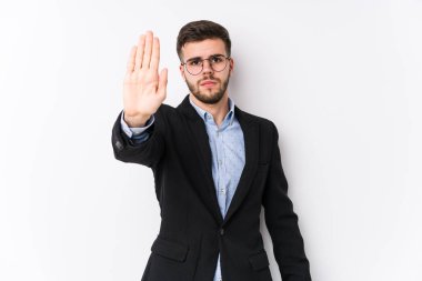 Beyaz arka planda poz veren beyaz tenli genç beyaz iş adamı elini uzatıp dur işareti göstererek seni engelliyor..