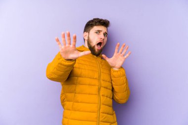 Mor arka planda izole genç bir adam yakın bir tehlike nedeniyle şoka uğruyor.