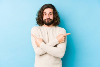 Mavi arka plan noktalarında izole edilmiş genç, uzun saçlı adam iki seçenek arasında seçim yapmaya çalışıyor..