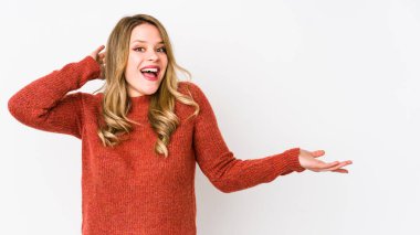 Beyaz arka planda izole edilmiş genç beyaz kadın avuç içinde fotokopi alanı tutuyor, el üstünde tutuyor. Şaşırmış ve mutlu..