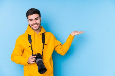 Kafkasyalı genç fotoğrafçı, avucunun içinde bir fotokopi alanı gösterip belinde bir el daha tutuyor..