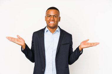 Genç iş adamı beyaz arka planda izole edilmiş. Kafası karışmış ve omuz silkiyor. Kopya alanını tutmak için..