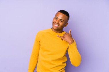 Mor arka planda izole edilmiş genç latin adam parmakları olan bir cep telefonu hareketi gösteriyor..