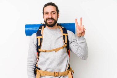 Genç bir sırt çantalı adam beyaz bir arka planda izole edilmiş zafer işareti gösteriyor ve gülümsüyor..