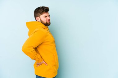 Mavi arka planda izole edilmiş beyaz bir adam sırt ağrısı çekiyor..