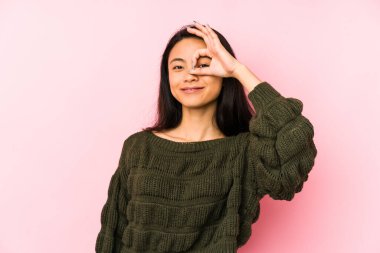 Genç Çinli bir kadın pembe bir arka planda izole edilmiş. Heyecanlı..