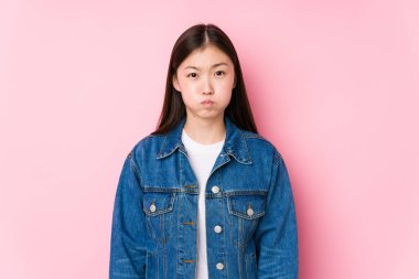 Pembe arka planda poz veren Çinli genç bir kadın yalnız yanaklara vuruyor, yorgun bir ifade takınıyor. Yüz ifadesi kavramı.