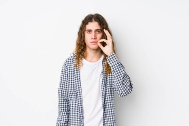 Uzun saçlı, yalnız poz veren genç adam dudaklarında parmaklarıyla bir sır saklıyor..