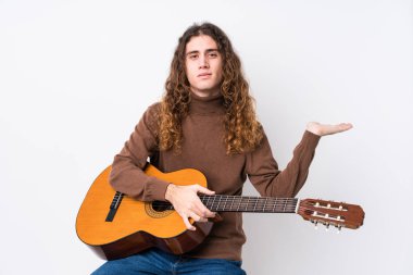 Gitar çalan beyaz bir adam avucunun içinde bir fotokopi alanı gösteriyor ve başka bir eli belinde tutuyor..