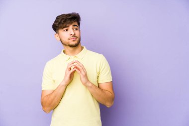 Genç Arap bir adam, mor bir arka planda izole edilmiş bir plan kuruyor, bir fikir kuruyor..
