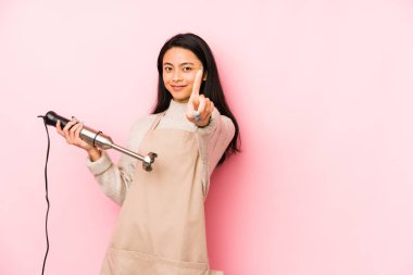 Bir mikser tutan genç Çinli kadın mutlu, güler yüzlü ve neşeli..