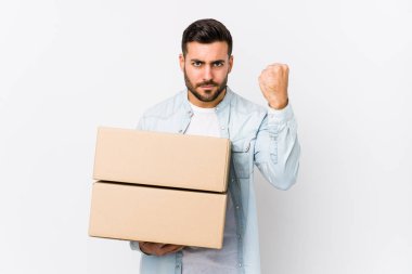 Genç, beyaz bir adam yeni evine taşınıyor, izole edilmiş, yumruğunu kameraya gösteriyor, agresif yüz ifadesi var..