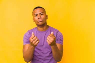 Sarı arka planda izole edilmiş genç latin adam hiç parası olmadığını gösteriyor..