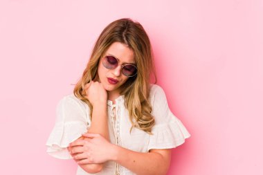 Gözlüklü genç beyaz kadın pembe arka planda izole edilmiş dirsek masajı yapıyor, kötü bir hareketin ardından acı çekiyor..