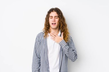 Genç, uzun saçlı, yalnız poz veren adam kahkahalar atıyor. Elini göğsünde tutuyor..