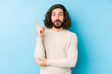 Genç, uzun saçlı bir adam mavi bir arka planda izole edilmiş. Harika bir fikri var. Yaratıcılık kavramı..