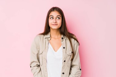 Pembe arka planda poz veren beyaz bir kadın hedeflerine ve amaçlarına ulaşmayı hayal ediyor.